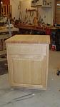 The cabinet is made of maple. It has a drawer and the trash cans sit on a shelf that slides out.